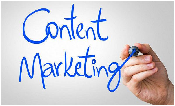 A hand writing the words "Content Marketing" in blue marker on a whiteboard.